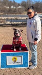 A Woman Standing Next To A Dog On A Box